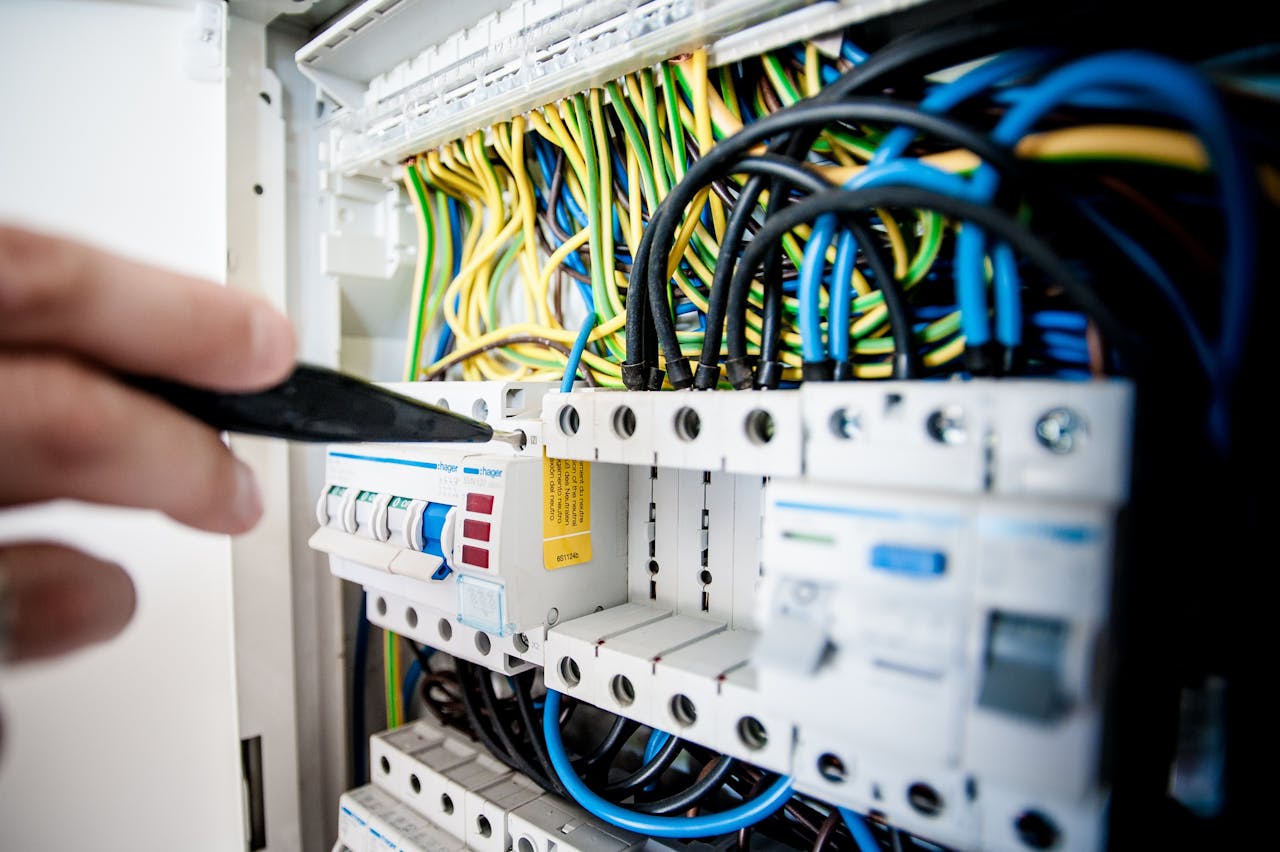 our-journey-03 Hand of electrician working on a circuit breaker panel with colorful wires, ensuring safe electrical connections.