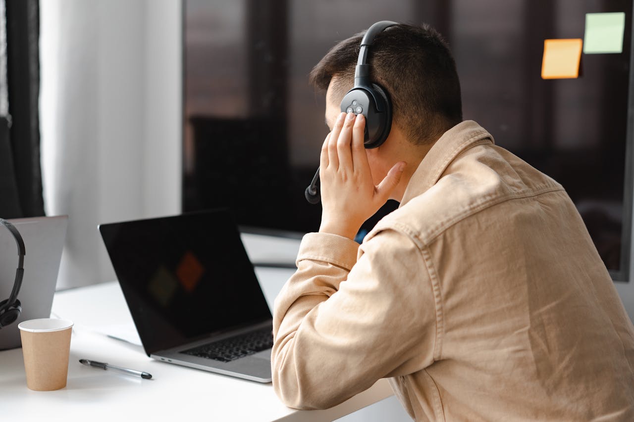 our-journey-01 A man wearing headphones works at a laptop in a modern office setting.